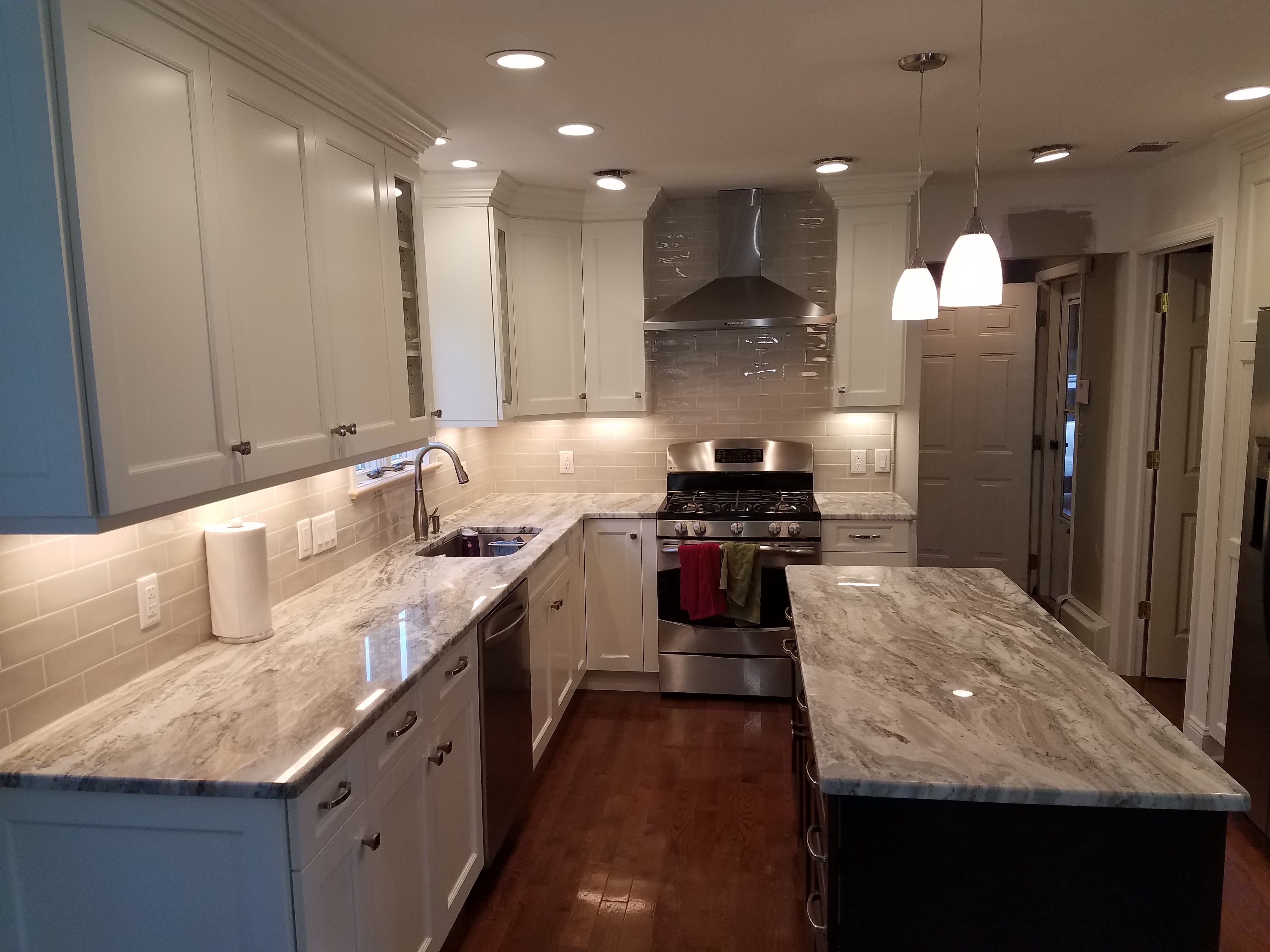 White shaker cabinets pair with a light gray subway tile backsplash and white quartz countertops with gray veining.