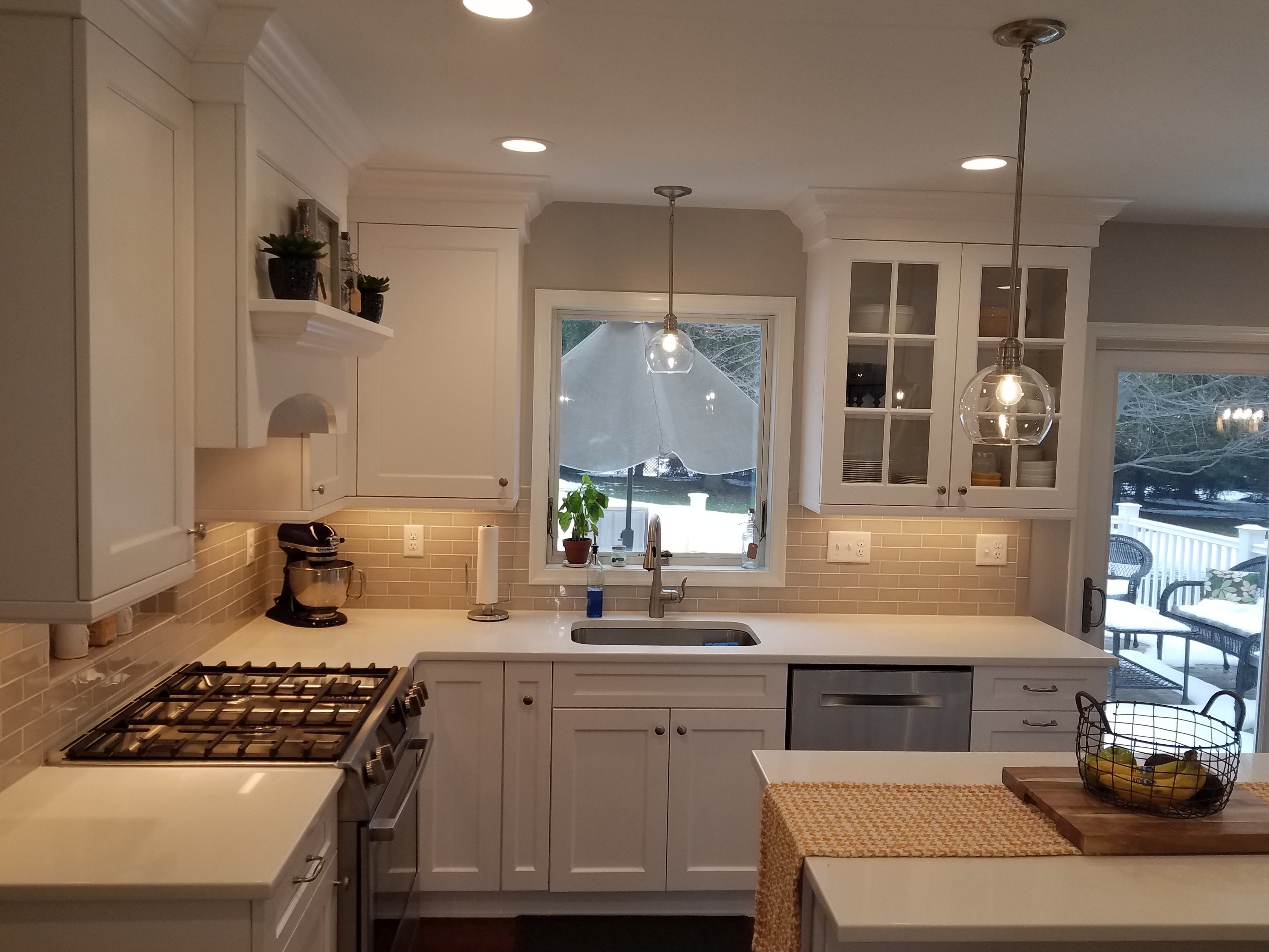 White shaker cabinets, a tan subway tile backsplash, and a stainless steel gas range and dishwasher furnish this kitchen.
