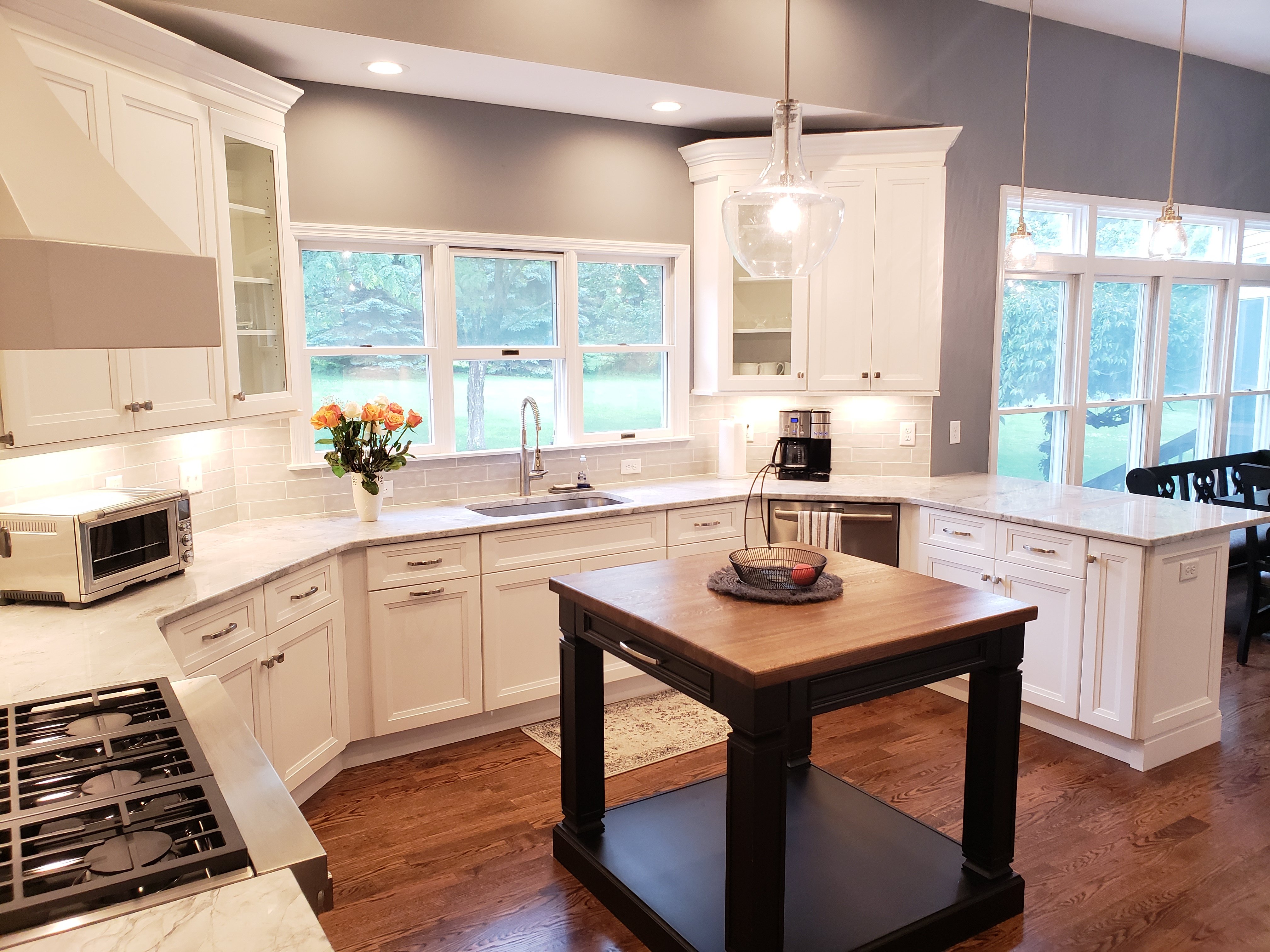 White shaker cabinets pair with light gray quartz countertops and a beige subway tile backsplash in this open kitchen.