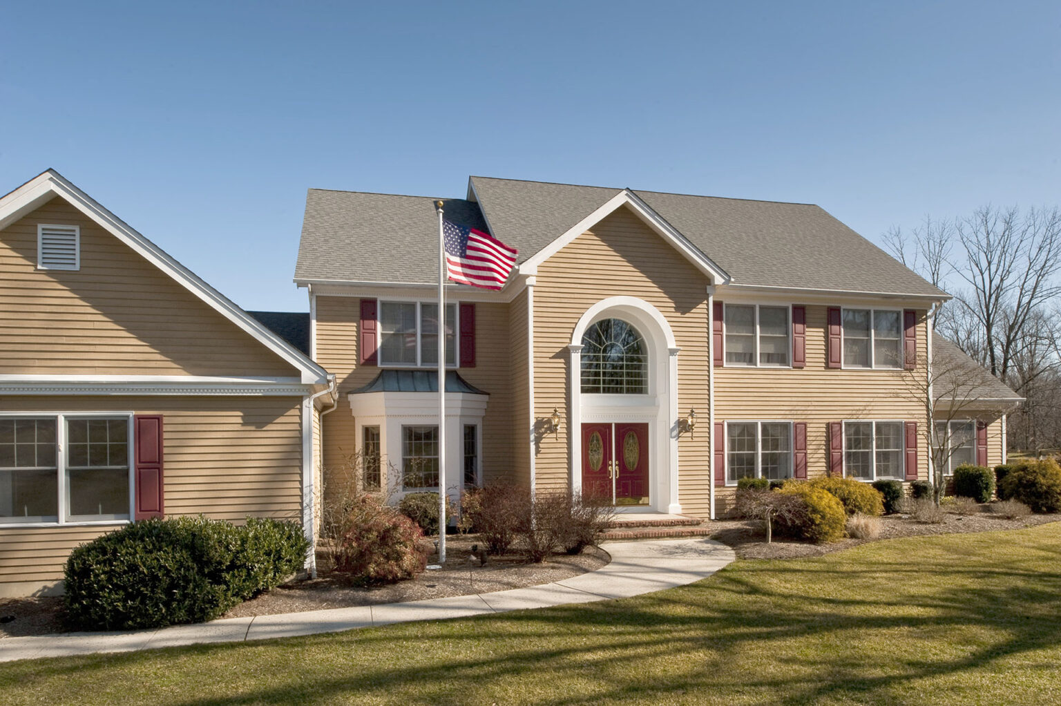 Two-story residential home with front lawn and American flag