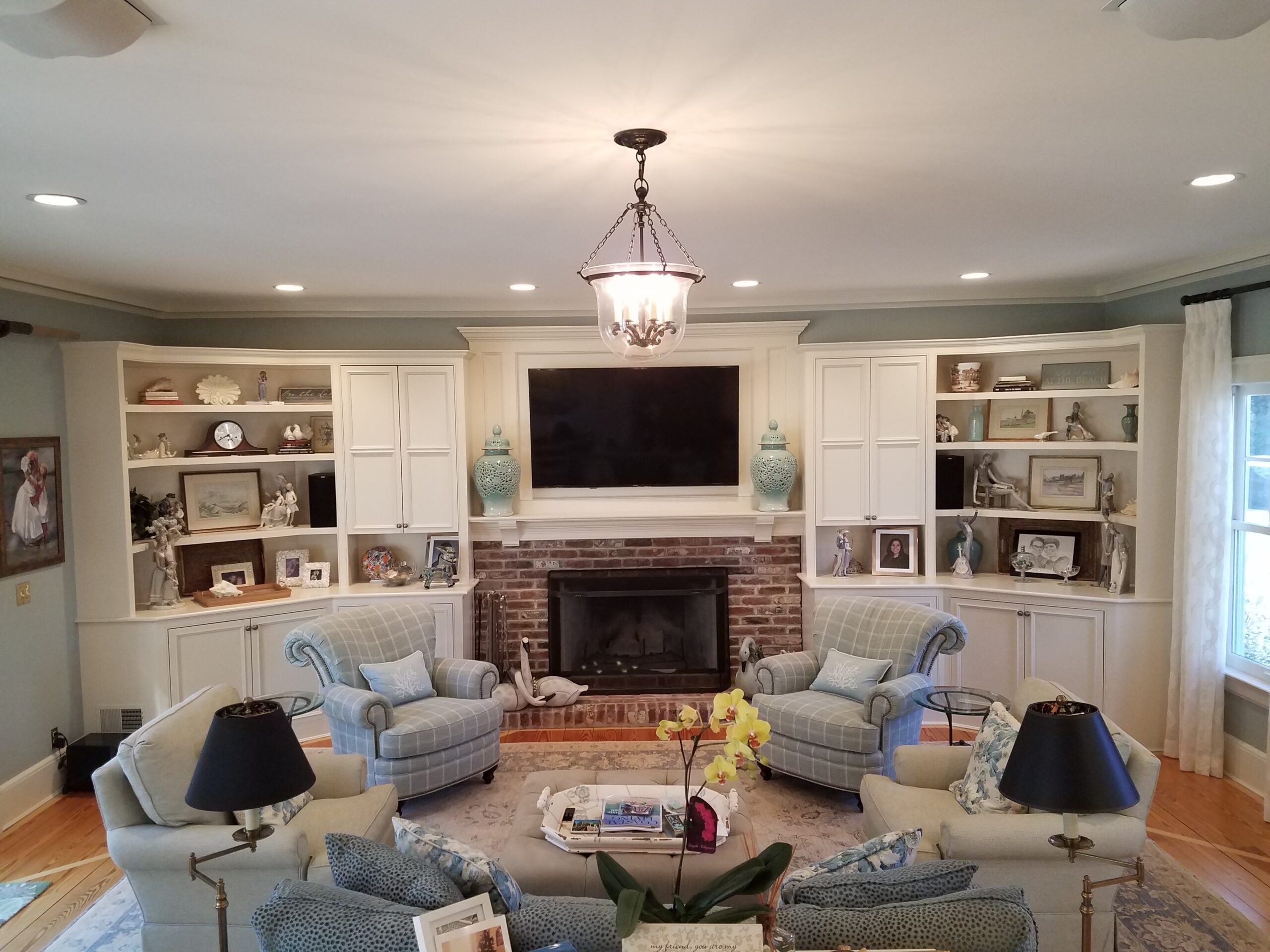 Cozy living room with white built-in shelves and large TV over fireplace