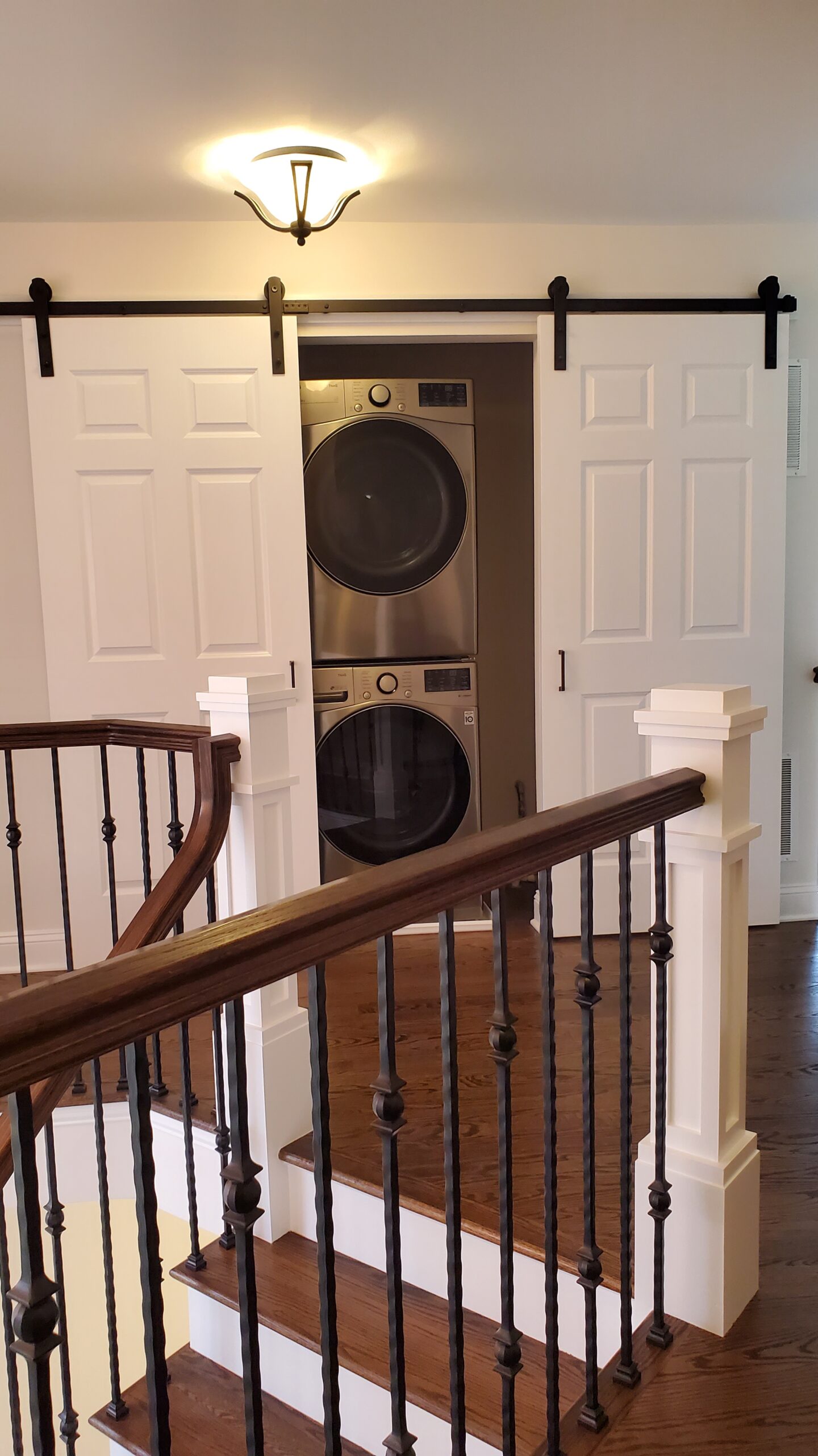 Curved staircase with dark handrail and laundry area view